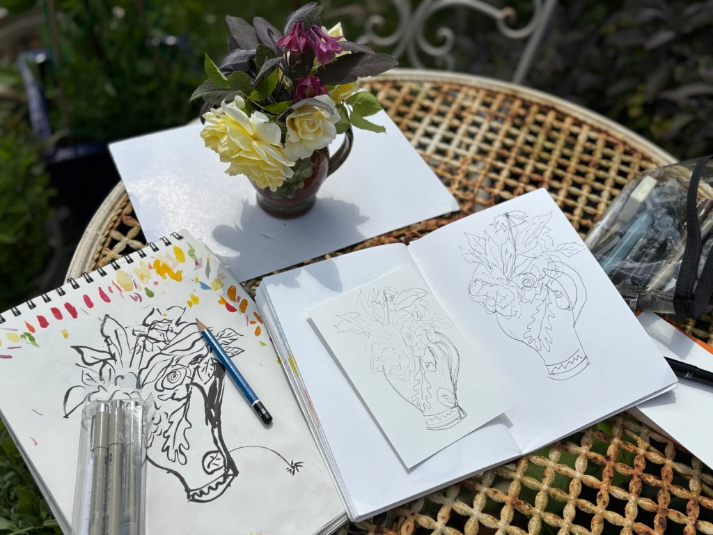 Jug of flowers on rusty outdoor table and art materials 